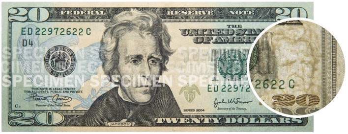 A $20 bill with a circular close-up of its faint portrait watermark.